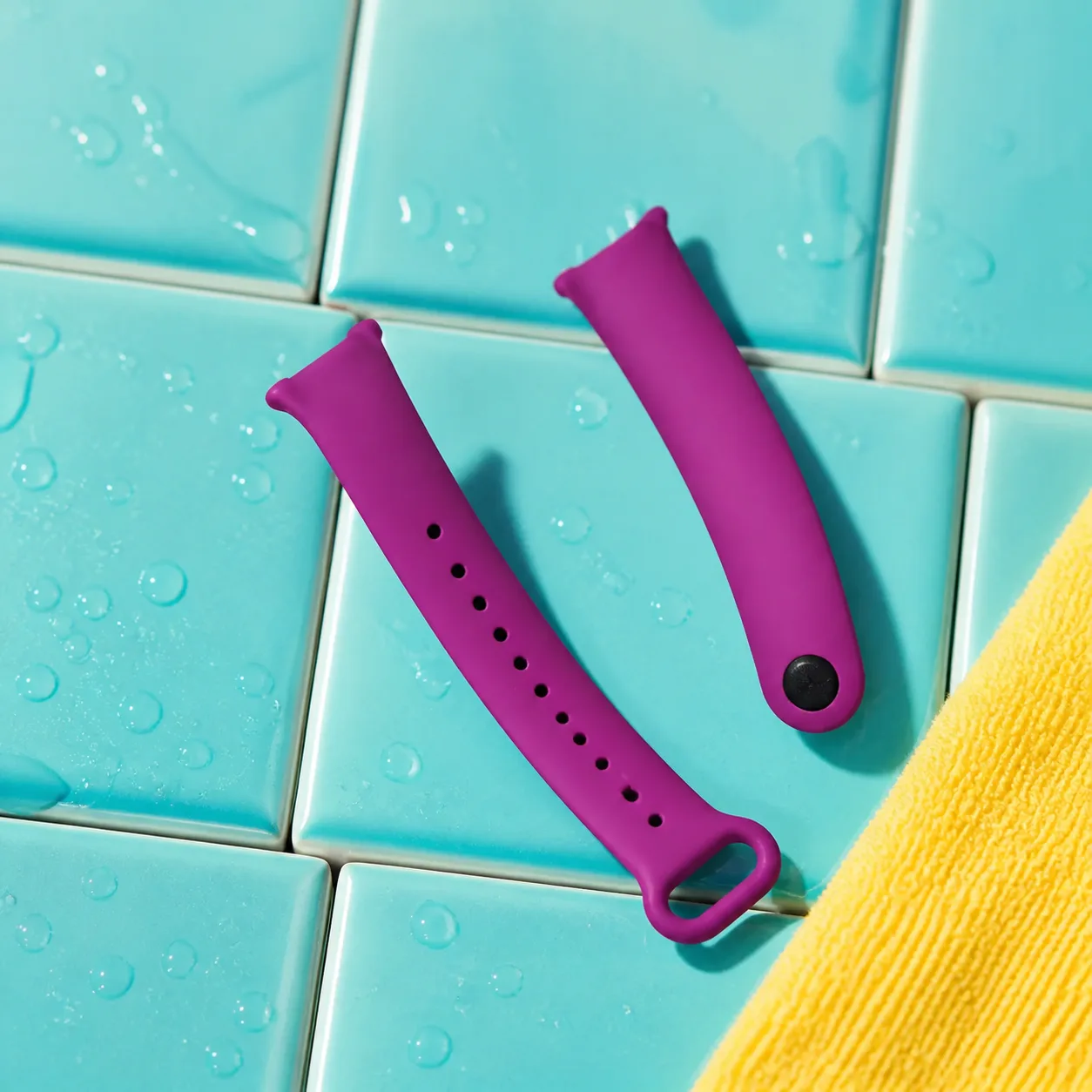 دو قطعه بند سیلیکونی بنفش Mi Band 9 روی کاشی فیروزه‌ای