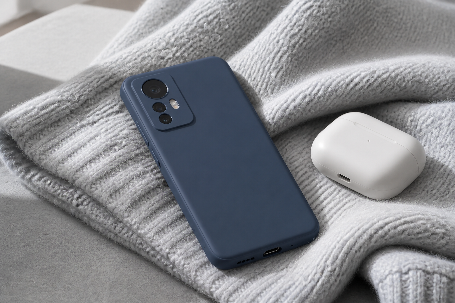 کاور سیلیکونی سرمهای نصبشده روی Xiaomi 12 کنار هندزفری روی بافت خاکستری