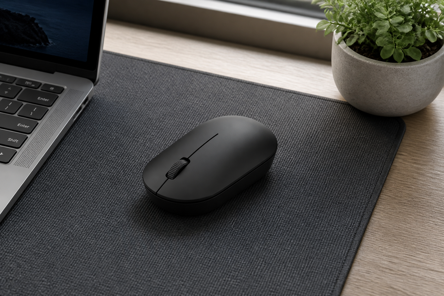 موس مشکی Xiaomi Wireless Mouse Lite 2 با یک چرخ اسکرول روی میز کار کنار لپ‌تاپ