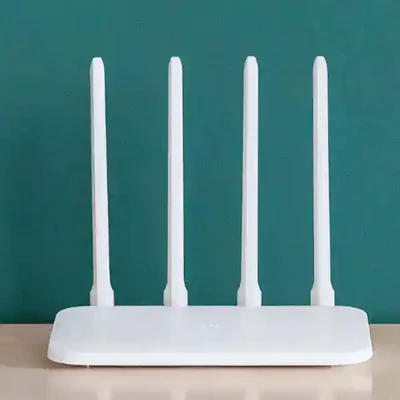 چهار آنتن روتر وایفای Xiaomi 4C در محیط داخلی روتر Xiaomi 4C روی میز با پسزمینه سبز تیره